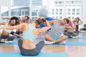 People with trainer doing pilate exercises in a bright gymYoung