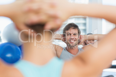 Smiling male with blurred people doing stretching exercises