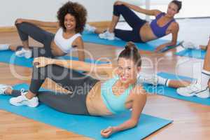 Smiling people doing pilate exercises in fitness studio