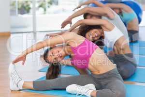 Sporty people doing stretching exercises in fitness studio