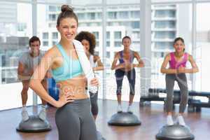 Smiling woman with fit people performing step aerobics exercise
