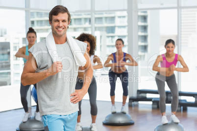 Man with fit people performing step aerobics exercise