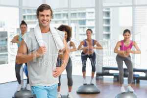 Man with fit people performing step aerobics exercise