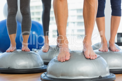 Low section of fit people standing on exercise equipment