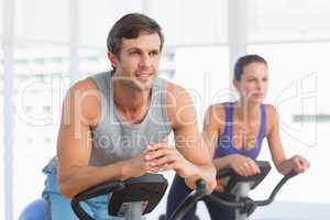 Smiling couple working out at spinning class