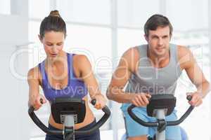 Smiling young couple working out at spinning class