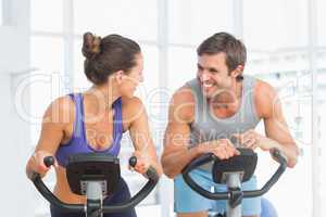 Smiling young couple working out at spinning class