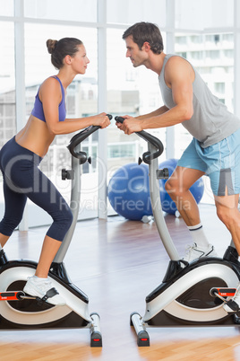 Side view of a couple working at spinning class in gym