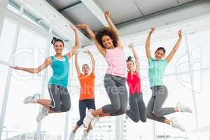 Fitness class and instructor jumping in fitness studio