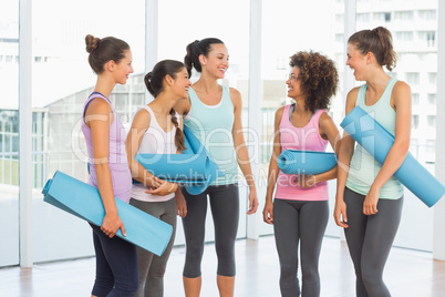 Fit smiling young women with exercise mats