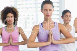Women in meditation pose with eyes closed at fitness studio