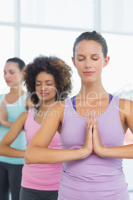 Women in meditation pose with eyes closed at fitness studio