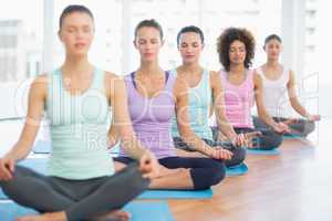 Sporty women in meditation pose with eyes closed at fitness stud
