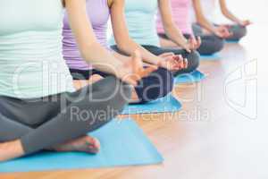 Sporty women in lotus pose at fitness studio