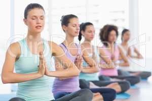 Young sporty women with joined hands sitting in row