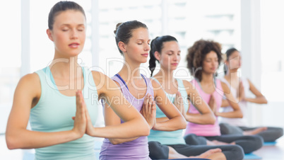 Young sporty women with joined hands sitting in row