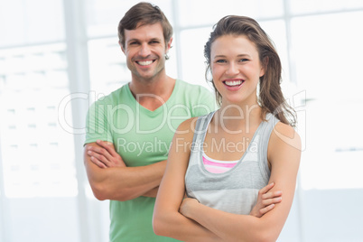 Fit young couple with arms crossed in exercise room
