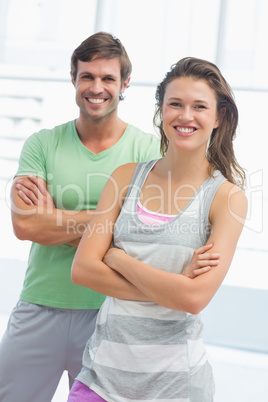 Portrait of a fit couple with arms crossed in exercise room