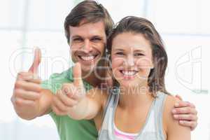 Portrait of a fit young couple gesturing thumbs up