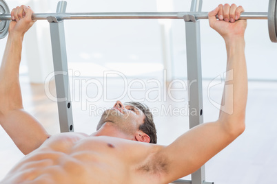 Shirtless fit man lifting the barbell bench press