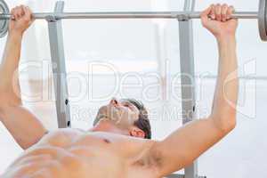 Shirtless fit man lifting the barbell bench press