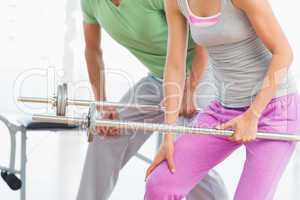 Mid section of fit couple holding barbells