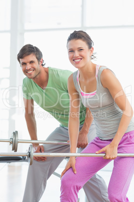 Fit young man and woman lifting barbells