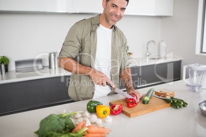 Smiling man chopping vegetables in kitchen