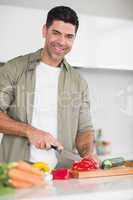 Smiling man chopping vegetables in kitchen