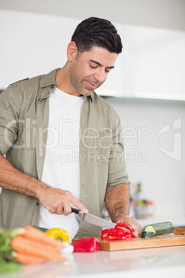 Smiling man chopping vegetables in the kitchen