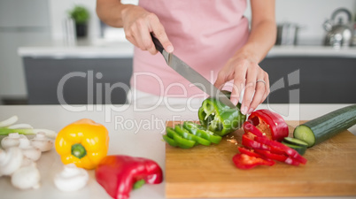 Mid section of a woman chopping vegetables in kitchen