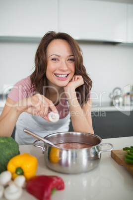 Smiling young woman preparing food in kitchen