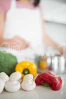 Vegetables with blurred woman preparing food in kitchen