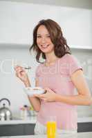 Smiling woman with a bowl of cereals in kitchen