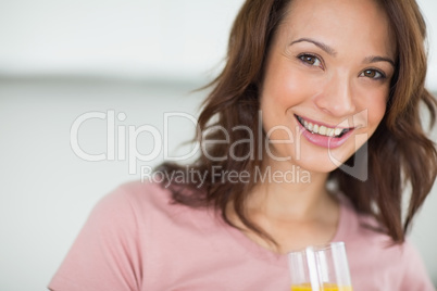 Closeup of a smiling woman holding orange juice