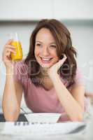 Woman with a bowl of cereals, orange juice and newspaper in kitc