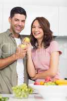 Portrait of a smiling couple with fruits in kitchen