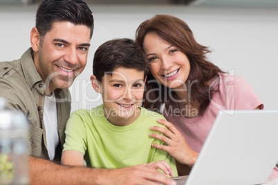 Smiling couple with son using laptop