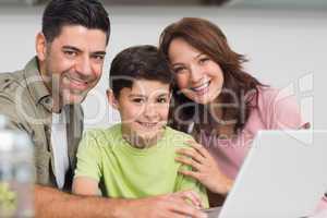 Smiling couple with son using laptop