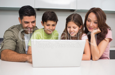Smiling couple with kids using laptop Smiling couple with kids using laptop