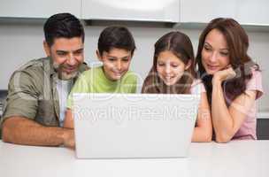 Smiling couple with kids using laptop