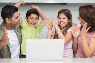 Cheerful couple with kids using laptop