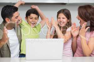 Cheerful couple with kids using laptop