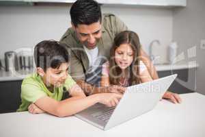 Father with kids using laptop in kitchen