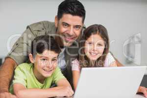 Smiling father with kids using laptop in kitchen