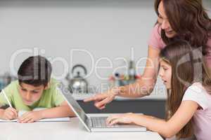 Mother with kids using laptop in kitchen