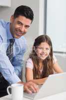 Father with daughter using laptop in kitchen