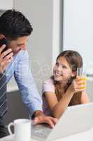 Smiling father with daughter using laptop in kitchen