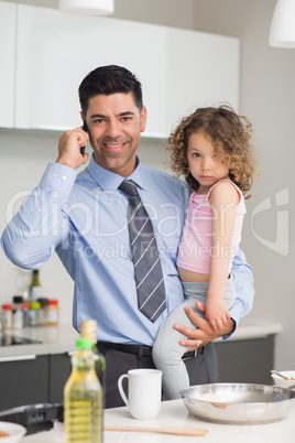 Well dressed father carrying daughter while on call