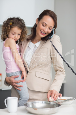 Well dressed mother with daughter preparing food while on call